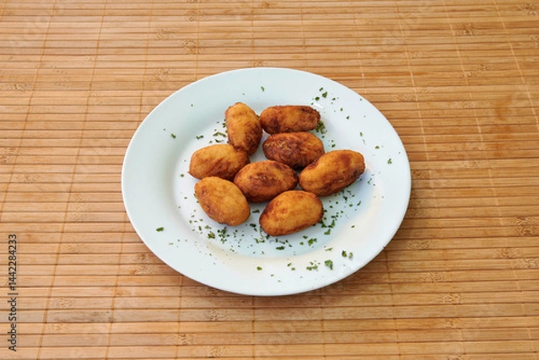 Obraz A plate of fried food with parsley on top. There are nine pieces of food on the plate