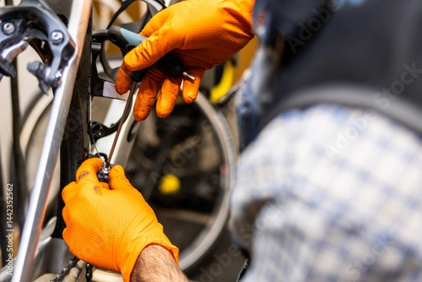 Fototapeta Bicycle mechanic repairing brakes with screwdriver in workshop
