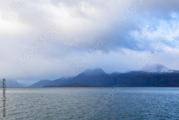 Fototapeta Autumn landscape of the Lyngen Alps in Northern Norway with snowy peaks, dramatic clouds, and a tranquil fjord.