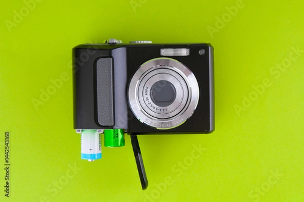 Obraz Old digital compact camera with alkaline AA batteries on a green background