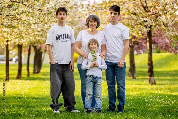 Obraz Portrait of cute stylish smiling family, boys and grandmother sitting in the grass in park