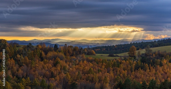 Obraz Sun rays shining through clouds over colorful autumn forest landscape with Low Tatras