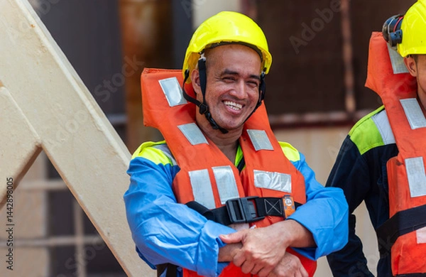 Fototapeta Crew members wear life jackets as they gather for an abandon ship drill, reviewing lifeboat deployment. Their safety gear and focused expressions underscore the critical nature of these exercises.