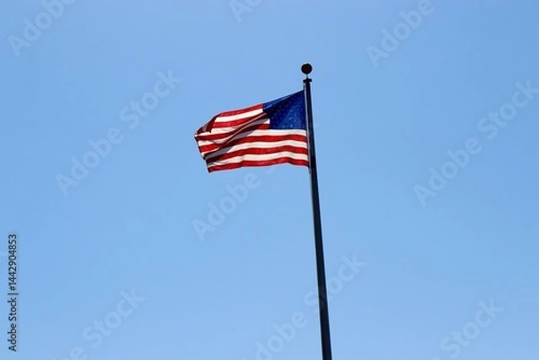 Obraz The American flag against the blue sky background.
