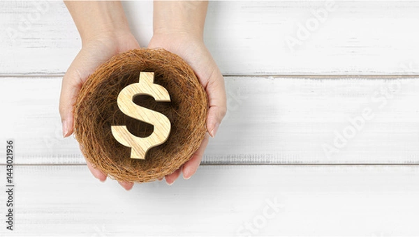 Fototapeta Financial Security and Growth: Hands Holding Wooden Dollar Symbol in a Nest