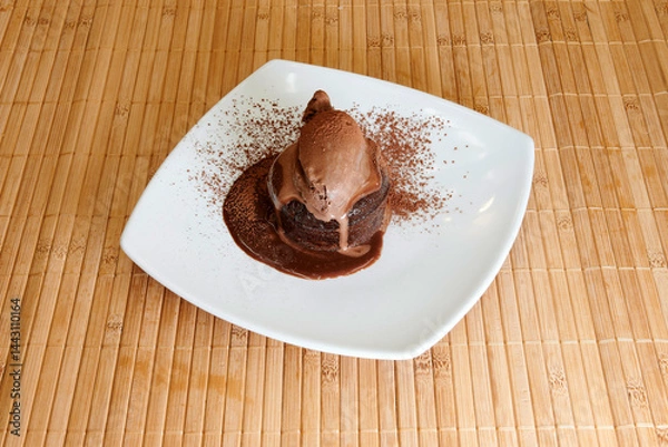 Obraz A chocolate dessert with a chocolate sauce drizzled on top. The dessert is on a white plate