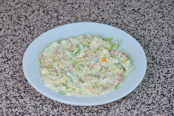 Obraz A white plate with a salad on it. The salad is made of lettuce, cheese, and ham