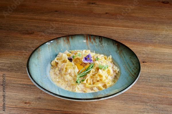 Obraz A bowl of pasta with a flower on top. The bowl is blue and the pasta is yellow