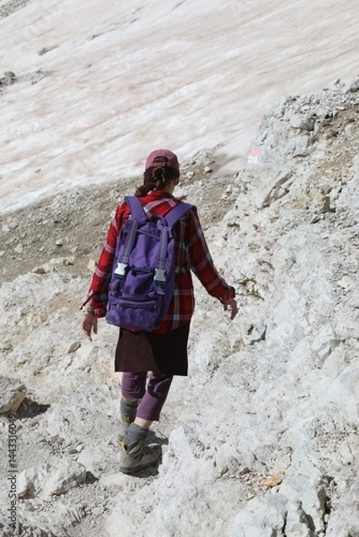 Obraz Woman walking on stony path with backpack on shoulders and hiking boots on feet