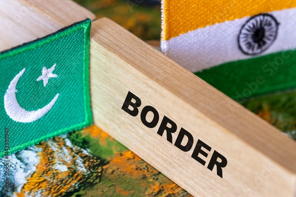 Obraz Pakistan-India border. Flags of India and Pakistan and a wooden block border symbol dividing the two countries. close up