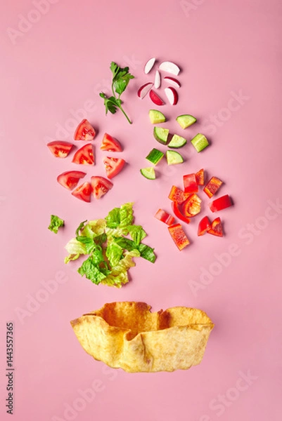Fototapeta Vegetable salad in tortilla bowl made from cucumbers, tomatoes, radishes, red bell peppers and lettuce.