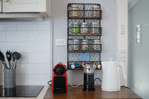 Obraz kitchen bench with coffee machine, milk spinner and kette. on the wall are power points with nothing plugged in, and a shelf of jars of tea, coffee and sugar, appliance