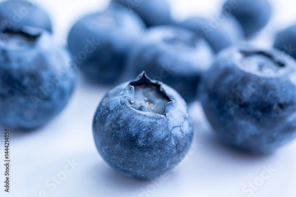 Fototapeta A cluster of blueberries, sits on a soft white surface, emphasizing freshness and texture.
