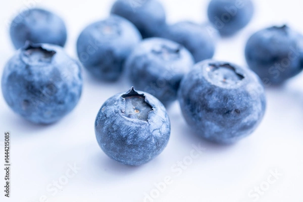 Fototapeta A cluster of blueberries, sits on a soft white surface, emphasizing freshness and texture.