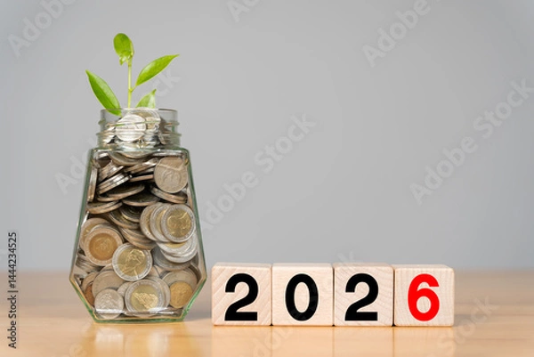 Fototapeta Business and new year concept 2026. Word 2026 written on white cube or block with coins in bottle.