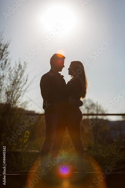Obraz Man and woman hugging in the background of the setting sun. Silhouette.