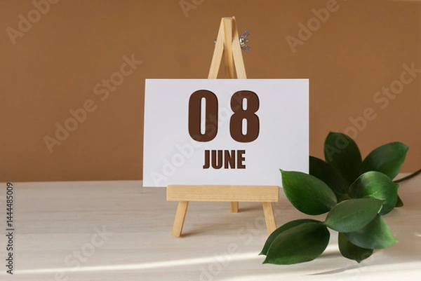 Fototapeta June 8th. Day 8 of month, Calendar date. Green branch, easel with the date and month on desktop. Close-up, brown background. Summer month, day of year concept