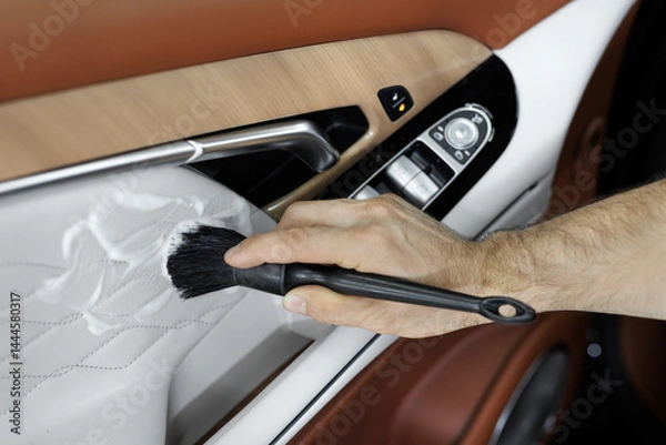 Fototapeta A man cleans the interior of a car with foam and a brush. Clean the door trim.