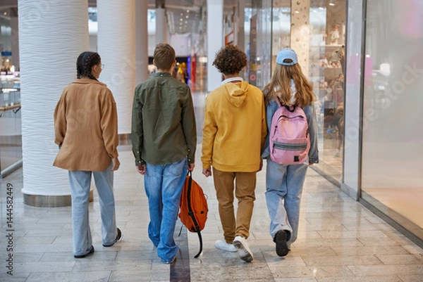 Obraz Group of teenagers fooling around running through shopping mall corridor