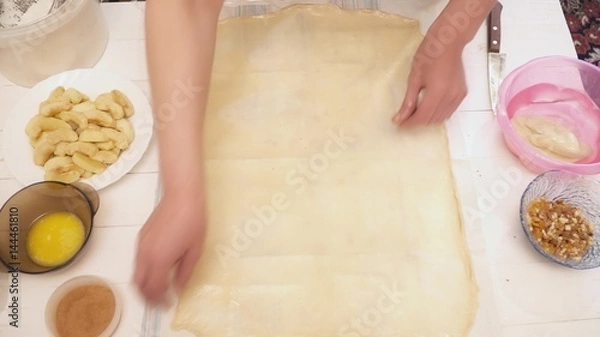 Fototapeta Woman's hands stretching the dough on the table