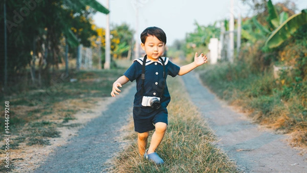 Fototapeta Asian boy learning how to use a video camera to post content on social media.