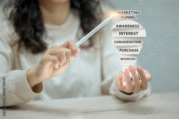 Obraz Woman using a stylus to point at a digital marketing funnel hovering over her hand.