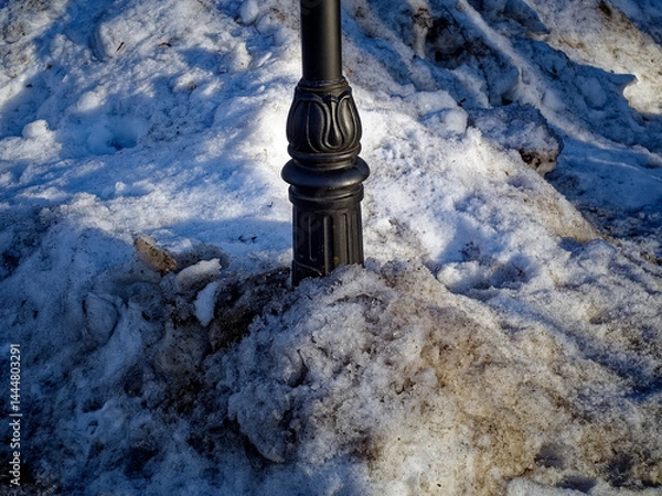 Obraz Street lamp pole in a snowdrift of dirty snow