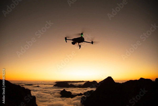Obraz Drone Silhouette in Sunset Light. High Mountains Peaks on Background with Clouds in a Valley. Clear sky, Low Light, Selective Focus.