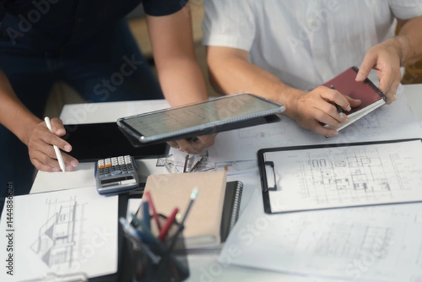 Obraz Two engineer businessman talking and brainstorming to planning about blueprint