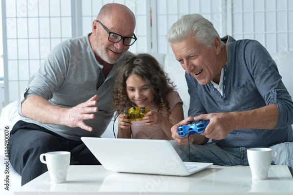 Fototapeta Two old men with granddaughter playing on laptop 