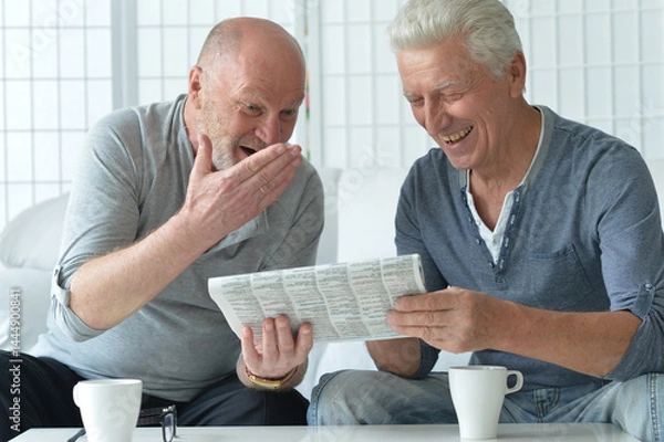 Fototapeta Two old men sitting at table and discussing news
