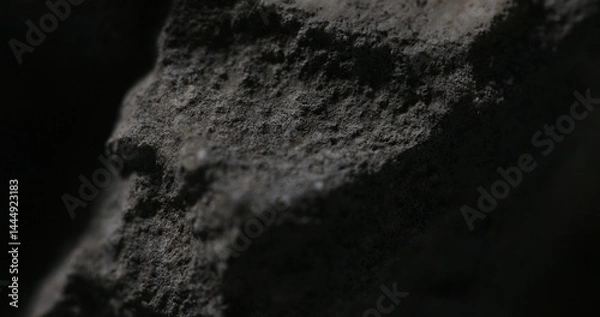 Fototapeta Dark close-up of volcanic rock with rough porous surface and shadow play