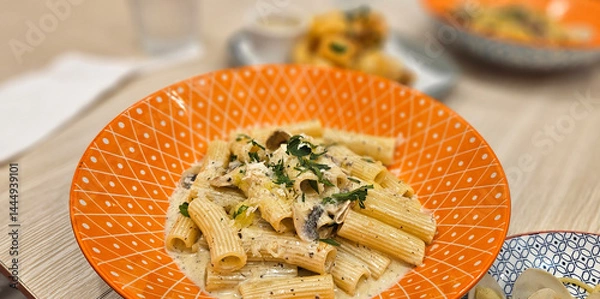 Fototapeta Mushroom penne pasta with cream truffle sauce serving on bright orange plate