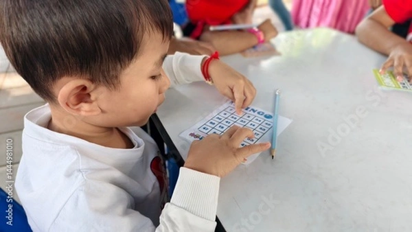 Obraz Child Playing Bingo Game with Focused Expression