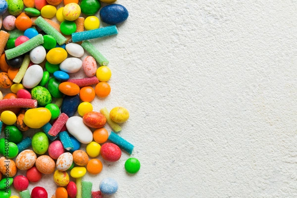Fototapeta Mixed collection of colorful candy, on colored background. Flat lay, top view. frame of colorful chocolate coated candy