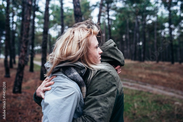 Fototapeta A loving guy with a girl is walking through the woods in the rain.