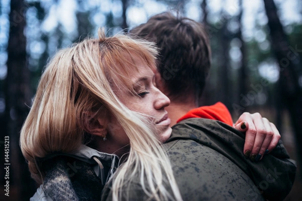 Fototapeta A loving guy with a girl is walking through the woods in the rain.