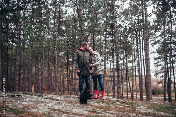 Fototapeta A loving guy with a girl is walking through the woods in the rain.