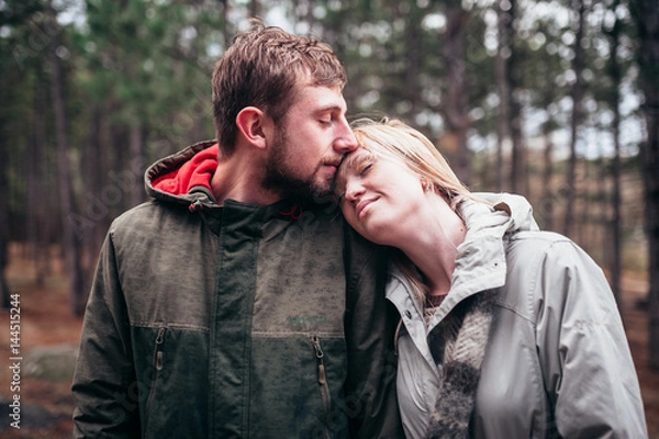 Fototapeta A loving guy with a girl is walking through the woods in the rain.
