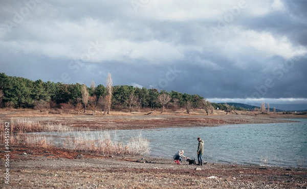Fototapeta Family walks with a dog in the forest near a river in the rain