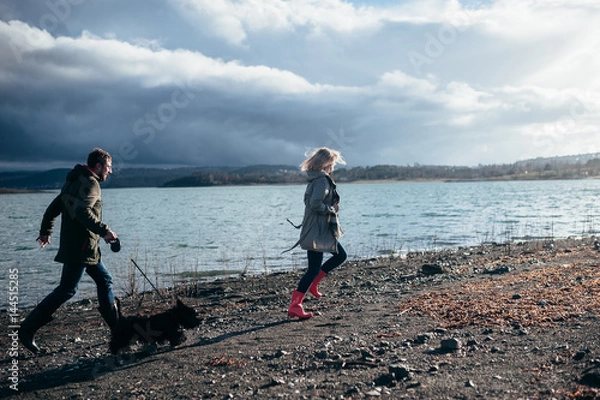 Fototapeta Family walks with a dog in the forest near a river in the rain
