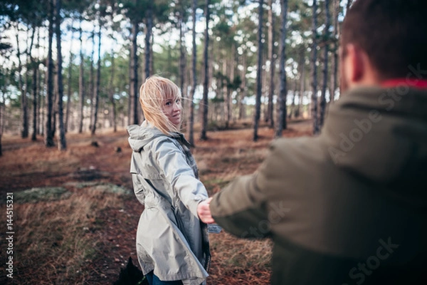 Fototapeta A loving guy with a girl is walking through the woods in the rain.