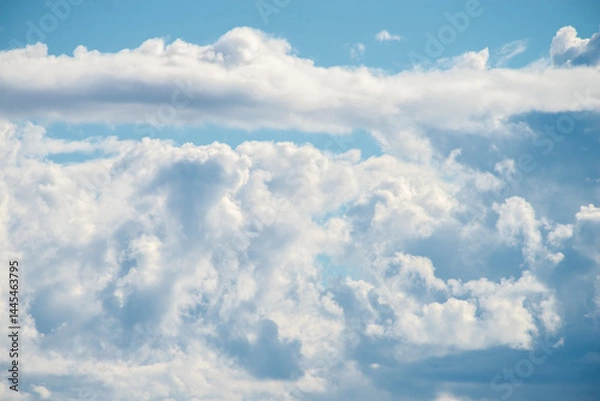 Fototapeta A cluster of cumulus thunderclouds in a bright blue sky during the daytime. Weather forecast. Thunderstorm formation. meteorology