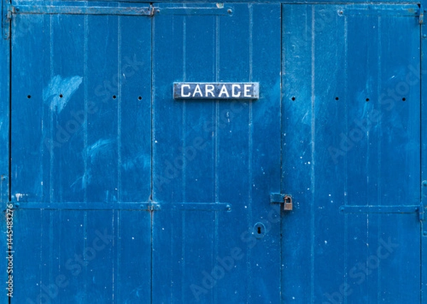 Obraz Blue wooden garage door with the inscription - Garage. Closed garage gate with a small lock on it