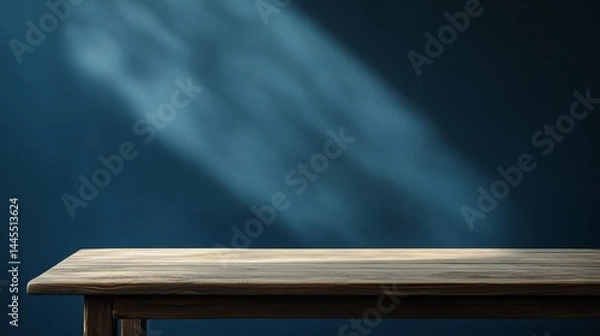 Fototapeta A blank table against a dark blue wall. Soft shadows and light add depth. Perfect to show off your products, like food or makeup.
