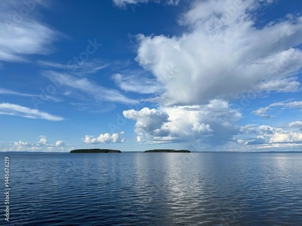 Obraz View of a tranquil lake with islands beneath a blue, partly cloudy sky in Sweden.
