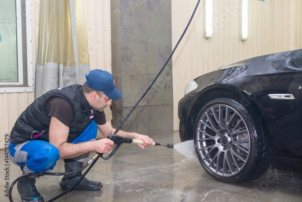 Obraz A man washes a black car