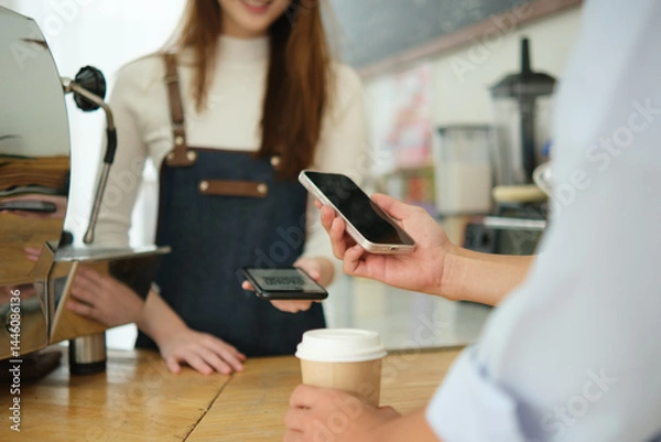 Fototapeta Customer making digital payment at coffee shop using smartphone.