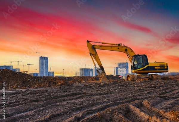 Obraz Excavator on construction site. Buildings under construction on sunset. Excavator on groundwork. Backhoe on roadworks. Excavator on earthworks. Heavy machinery equipment on excavation on sunset.