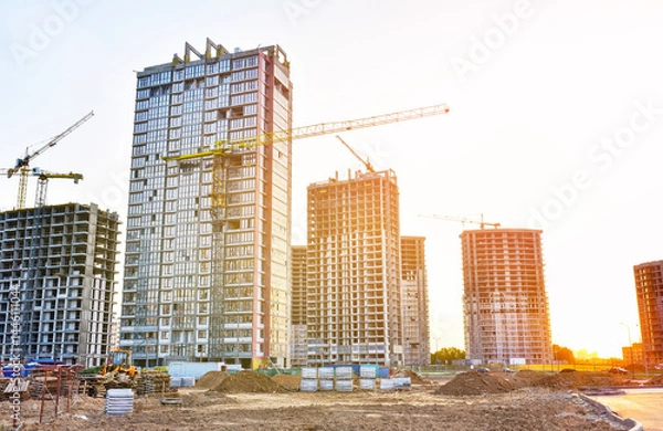 Obraz Construction site on sunset. Construction crane on Housing. Buildings under construction. Tower cranes in action. Crane during formworks. Multi Storey Residential Buildings construction.